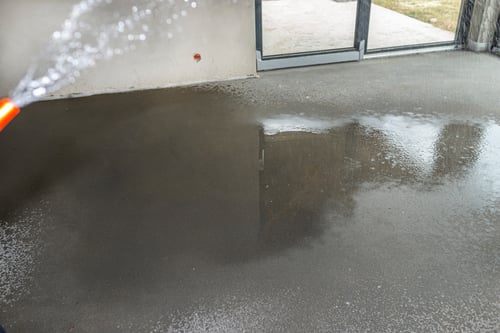 Garage concrete slab being rinsed with water during surface preparation